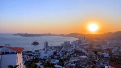 Atardecer en Acapulco, mostrando el cielo teñido de colores vibrantes sobre la playa, con personas disfrutando de la vista.